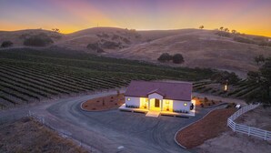 A vineyard with rows of grapevines and a house with a red roof. - Vineyard Views + Covered Patio | Paso Robles | Mission de los Robles (Paso Robles)