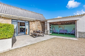 A stone building with a patio area, a wooden table, and outdoor seating.