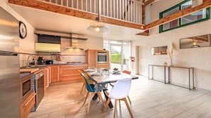 Une cuisine moderne avec des poutres en bois, un coin repas avec des chaises et une grande fenêtre.