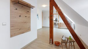 A spacious room with a wooden wall-mounted rack, a wooden staircase, and a dining area in the background. - Apartment 'Weinbergblick' with Balcony and Wi-Fi (Auggen)