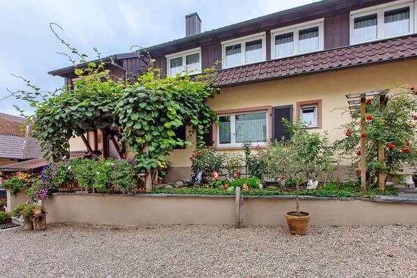 Una casa con jardín, camino de grava y valla de madera.