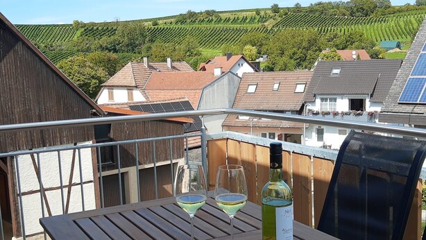 A balcony with a table, two wine glasses, and a bottle of wine. - Apartment 'Weinbergblick' with Balcony and Wi-Fi (Auggen)
