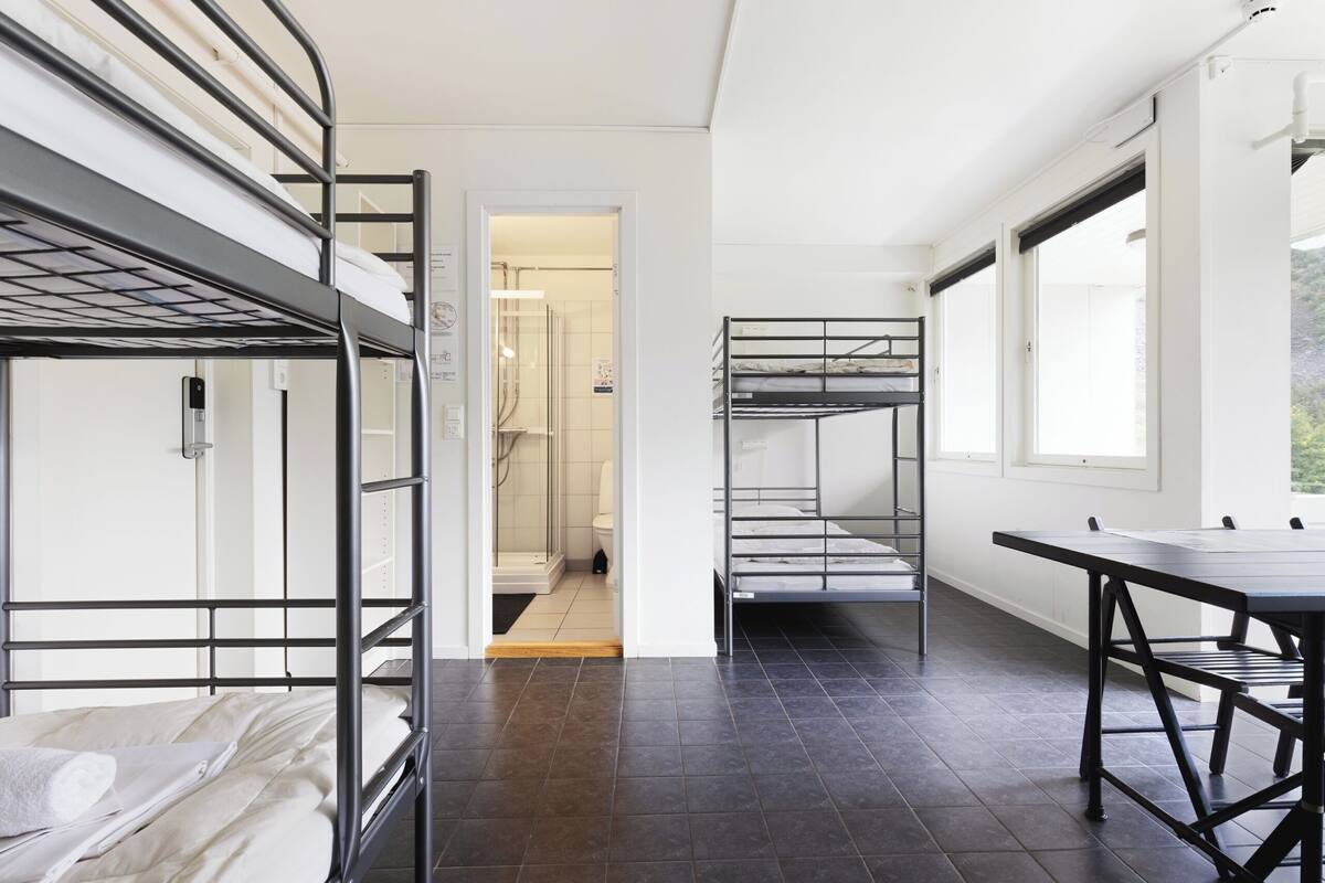 A room with bunk beds, a table, and a view through a doorway to a bathroom.