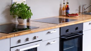 A modern kitchen with a wooden countertop, a built-in oven, and a black range hood. - Trolltunga Hostel (Ullensvang)