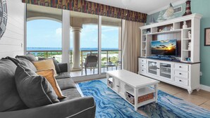 Ein Wohnzimmer mit Sofa, Fernseher und Meerblick.