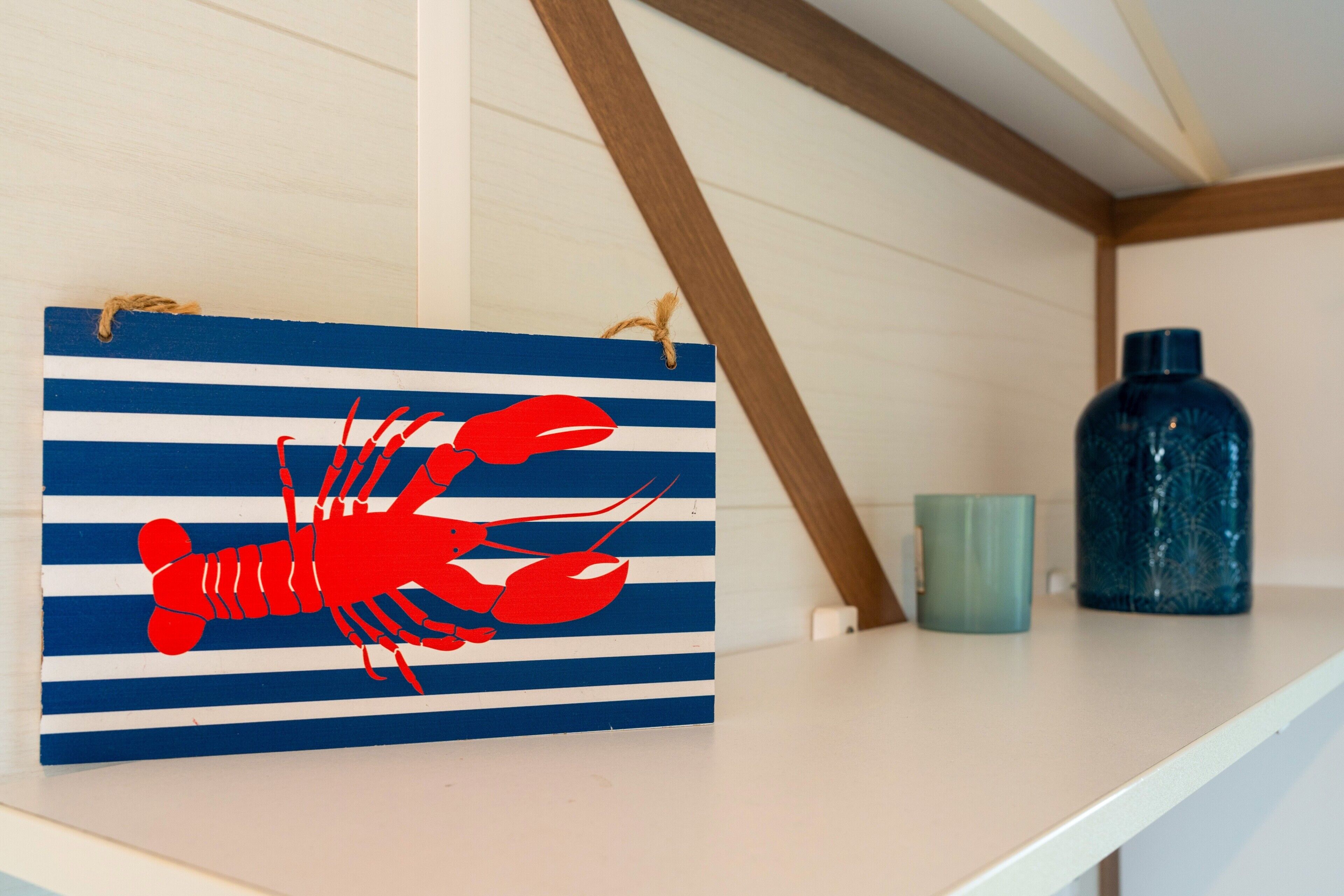 Un comptoir de cuisine orné d’un motif rayé rouge et bleu représentant un homard, une tasse verte et une bouteille d’eau bleue.