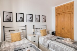 A hotel room with two beds, a wardrobe, and wall art.