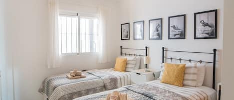 Un dormitorio con dos camas, una ventana con cortinas y una obra de arte colgada en la pared.