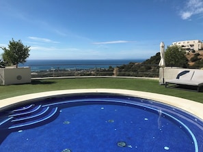 A swimming pool with a view of the sea and a building in the background.