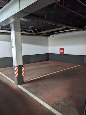 A parking garage with concrete pillars, a red emergency exit sign, and a clean, empty floor. - Amazing resort with several pools, gym, jacuzzi (Marbella)