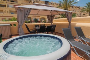 An outdoor hot tub area with a table and chairs, surrounded by a covered seating area. - Sea view from 3 terraces / Beach 10min / Hot tub (La Cala de Mijas)