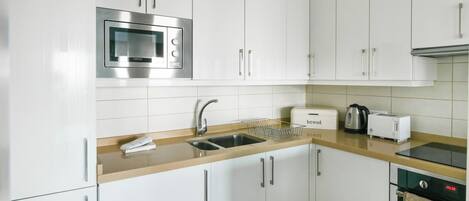 A modern kitchen with white cabinets, stainless steel appliances, and a built-in oven.