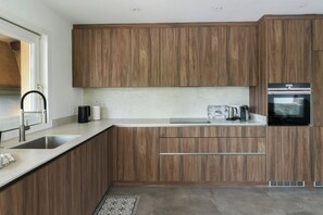 A modern kitchen with wooden cabinets, a stainless steel sink, and a built-in oven.
