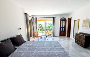 A bedroom with a bed, a desk, and a chair. There is a balcony with a view of greenery. - Luxury villa great views, pool, BBQ & outdoor bar (Mijas)