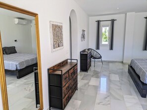 A bedroom with a bed, dresser, mirror, and a bicycle on the wall.