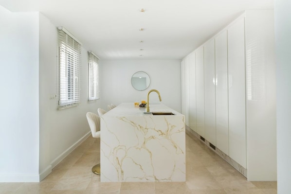 A modern bathroom with a marble vanity, a round mirror, and a gold faucet.