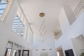Un intérieur spacieux avec de hauts plafonds, de grandes fenêtres et un luminaire décoratif suspendu.