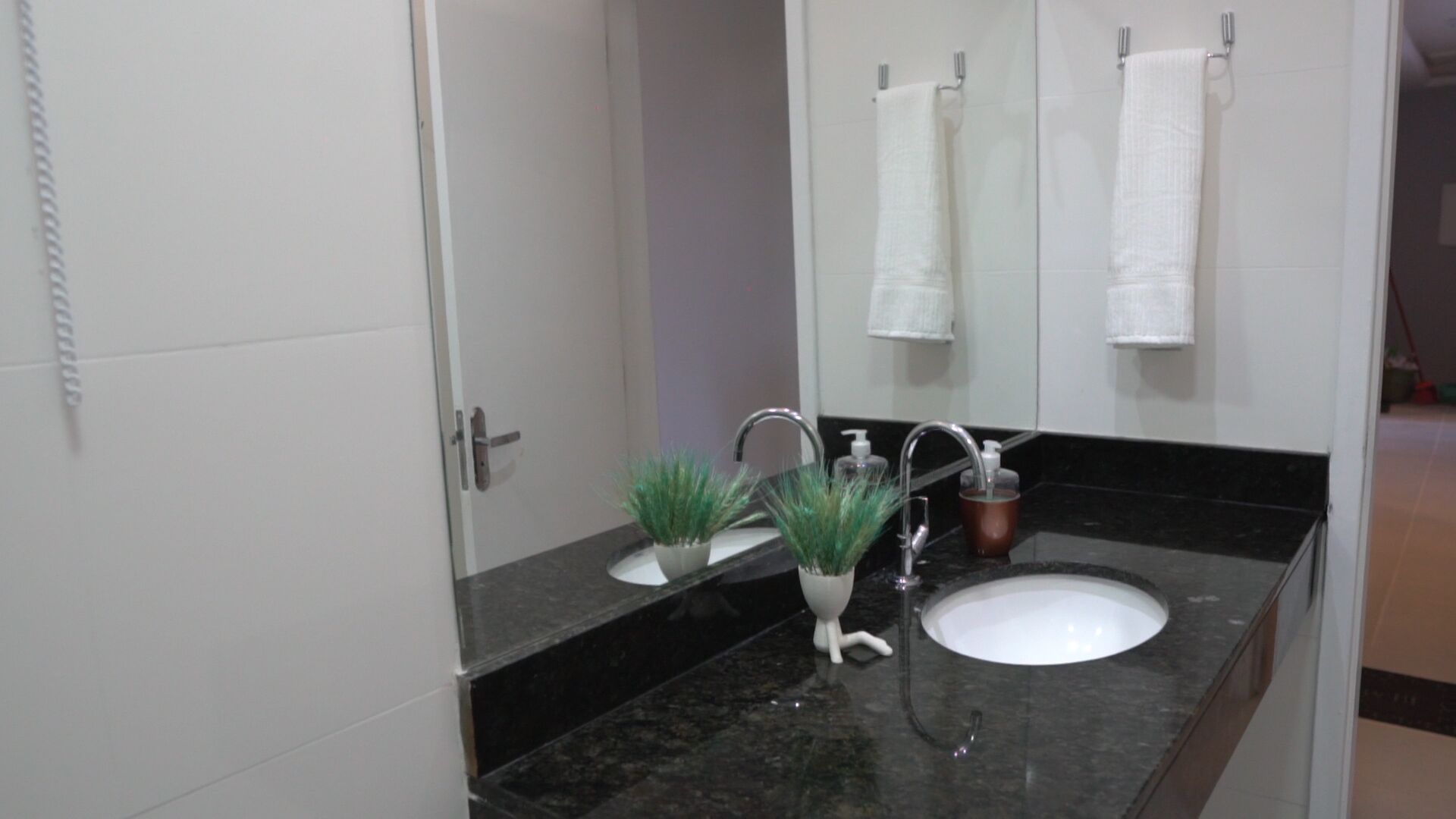 A bathroom with a white sink, a mirror, and a door with a handle.