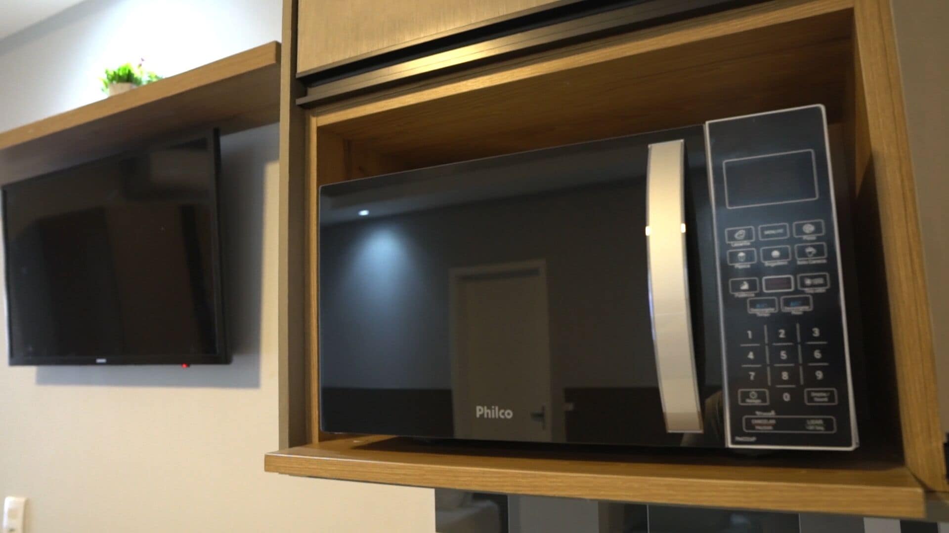A microwave oven with a control panel, placed in a wooden cabinet.