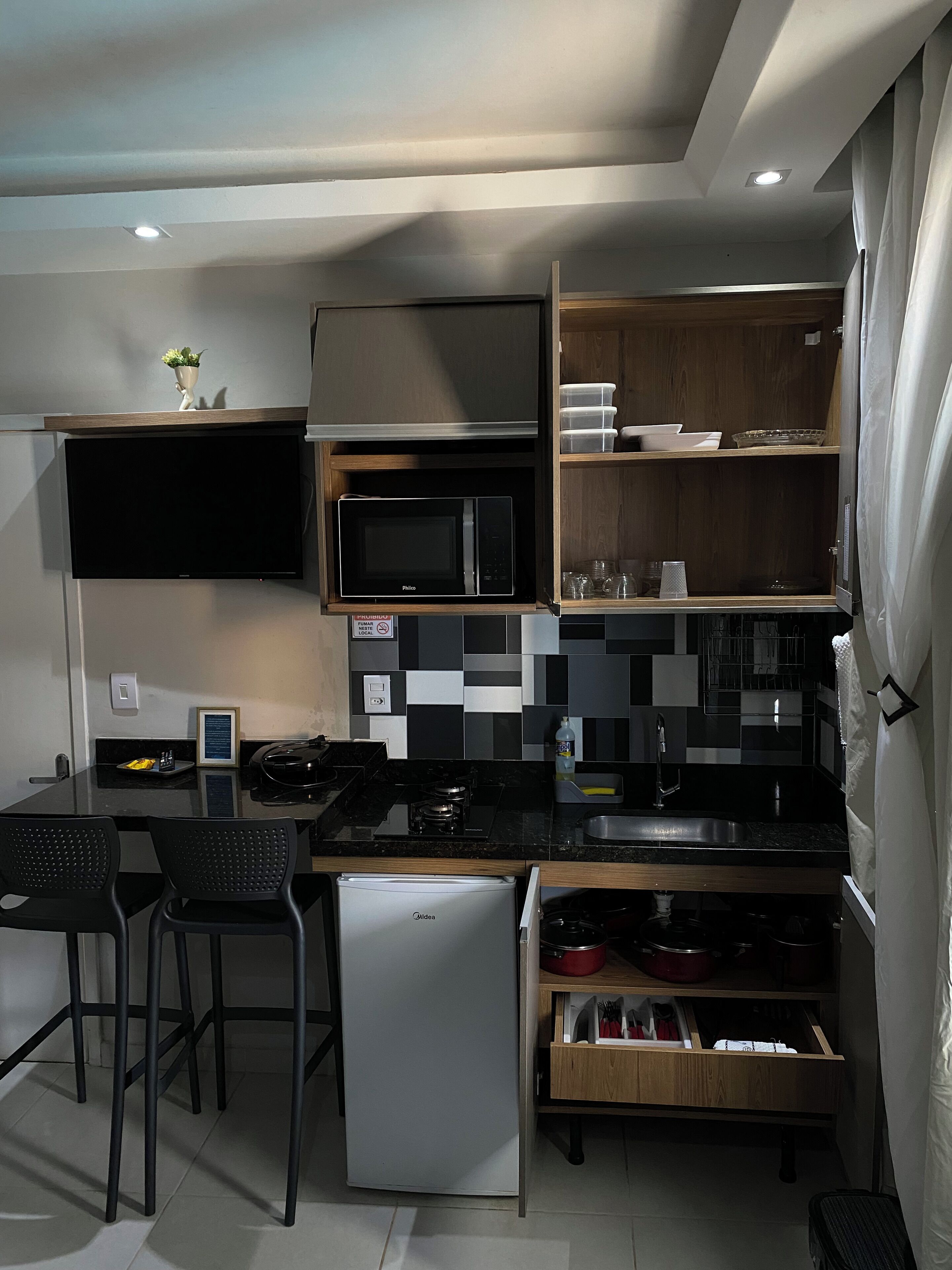 A compact kitchen with a built-in microwave, a small refrigerator, and a dining area with two chairs.