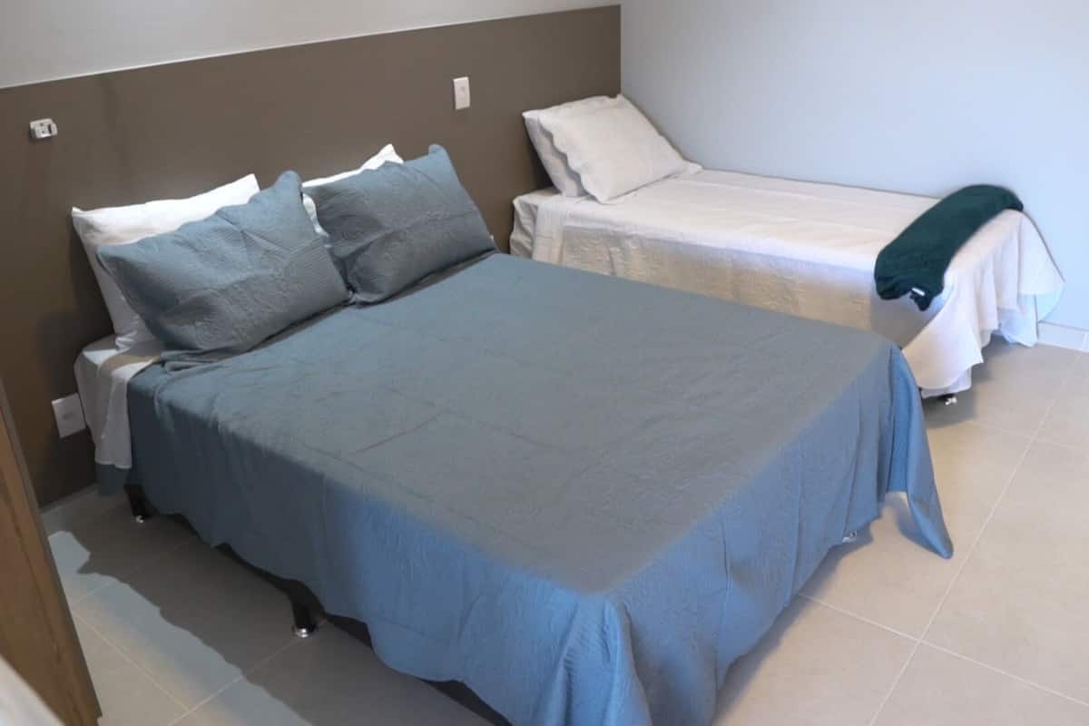 A bedroom with a large bed, two bedside tables, and a smaller bed in the corner.