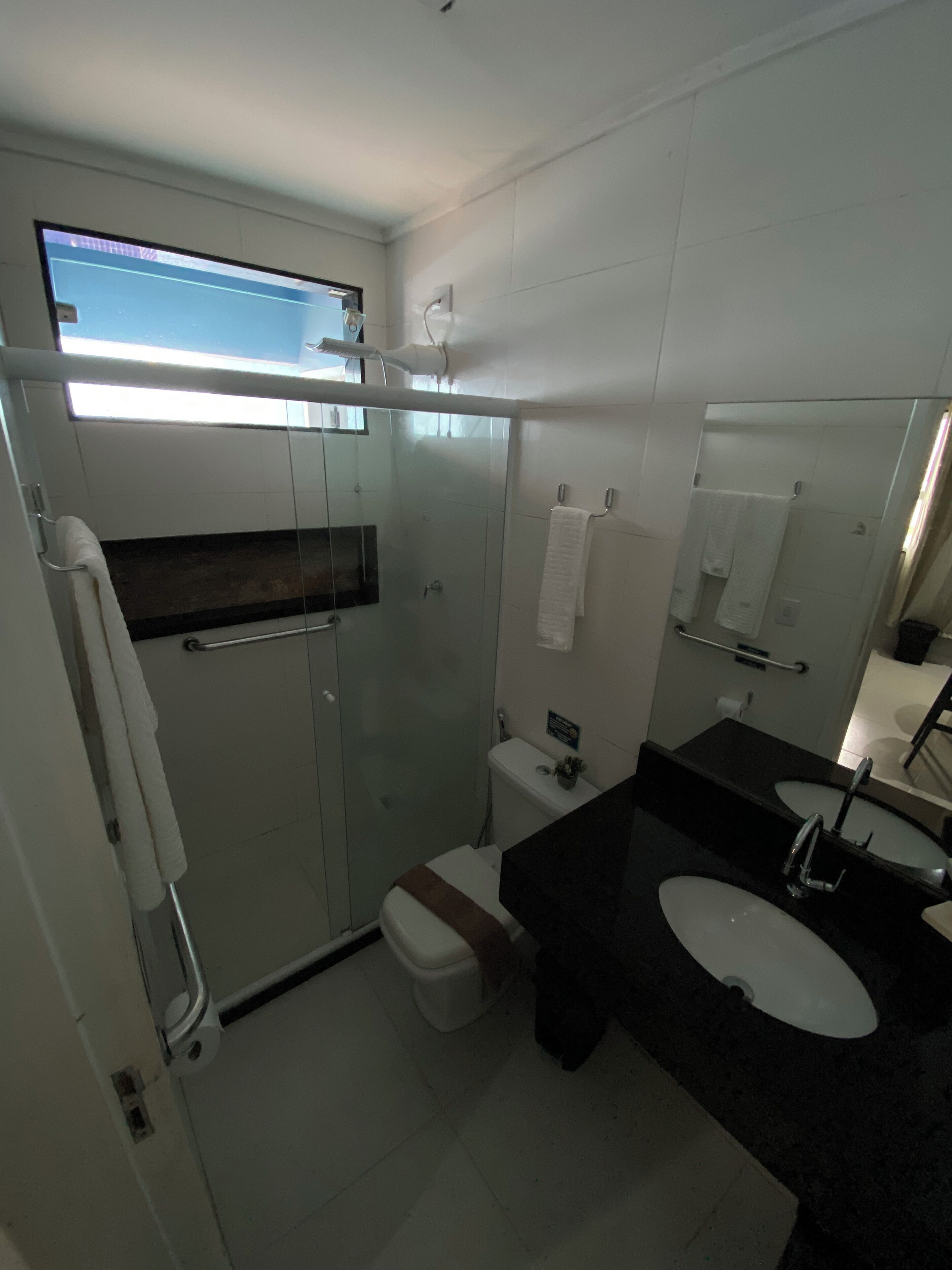 A modern bathroom with a glass-enclosed shower, a toilet, and a double sink vanity.