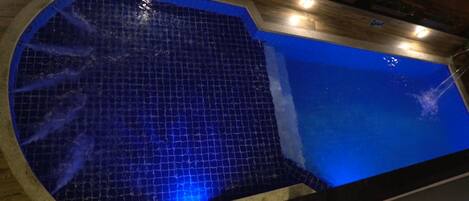 Una piscina con piso de azulejos azules y cubierta con una terraza de madera.