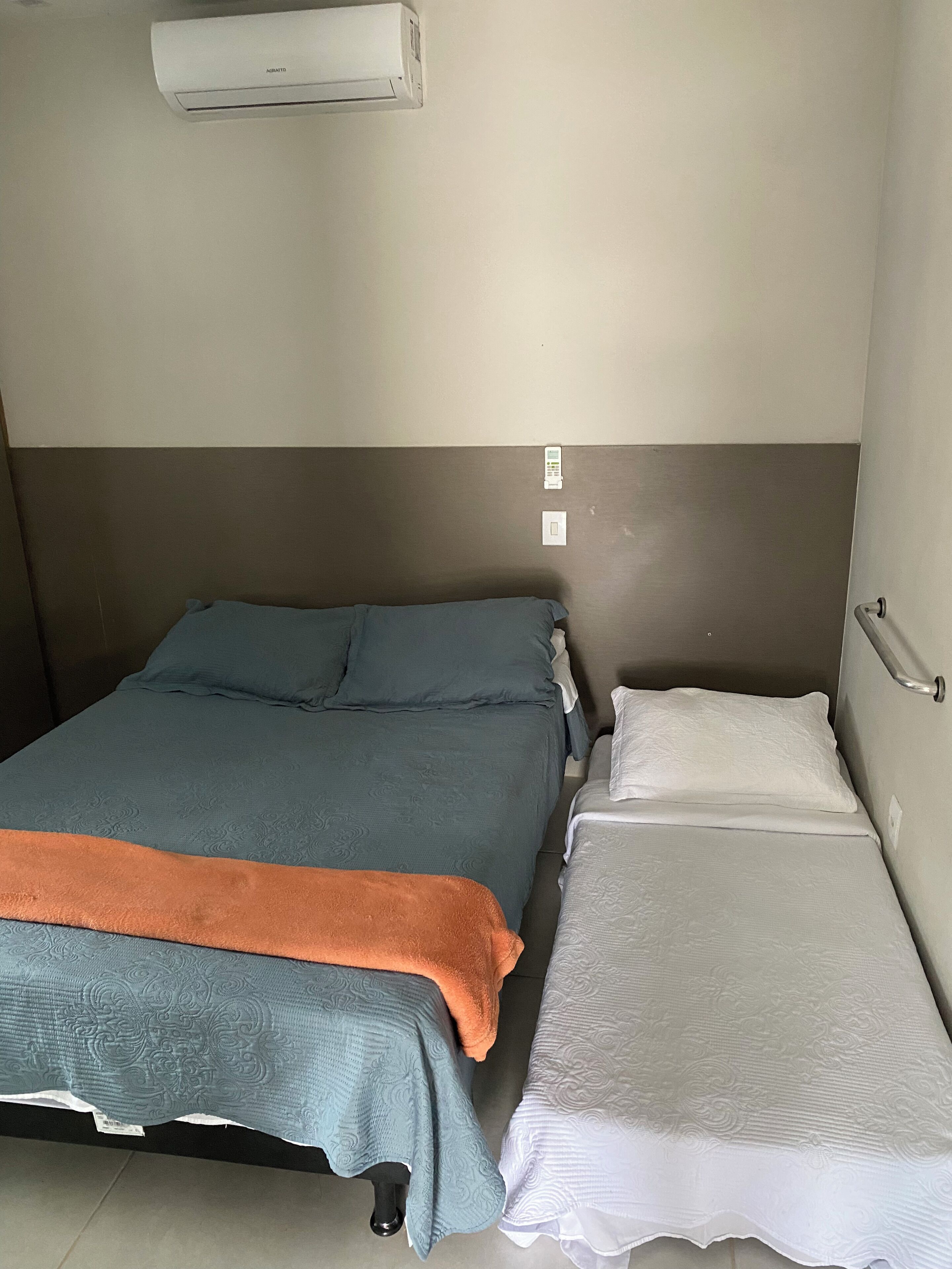 A room with a bed, a bedside table, and a wall-mounted air conditioner.