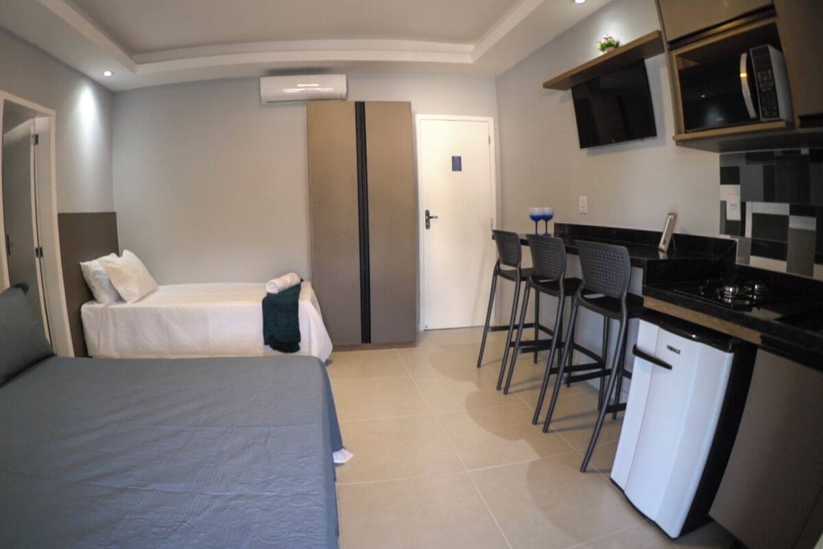 A compact hotel room with a bed, a small kitchenette, and a bathroom.
