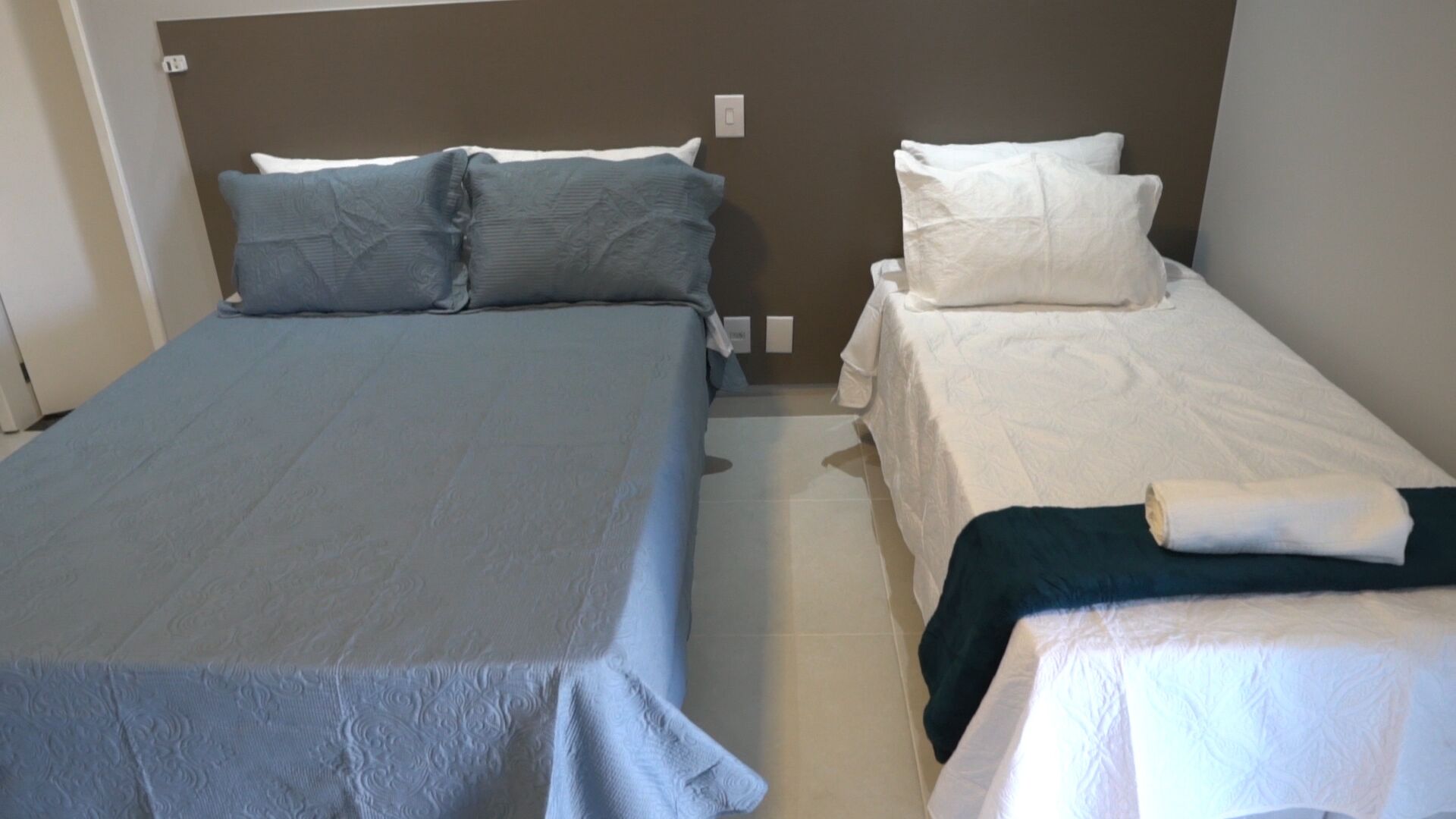 Hotellihuone, jossa on kaksi sänkyä, ja jokaisessa sängyssä on erivärinen peitto.