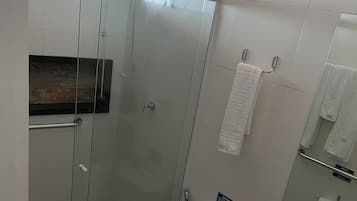 A bathroom with a glass-enclosed shower, a toilet, a sink, and a mirror.