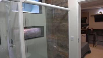 Une salle de bain moderne avec une douche à l’italienne en verre, un mur d’accent en bois et un espace cuisine ouvert avec des tabourets de bar.