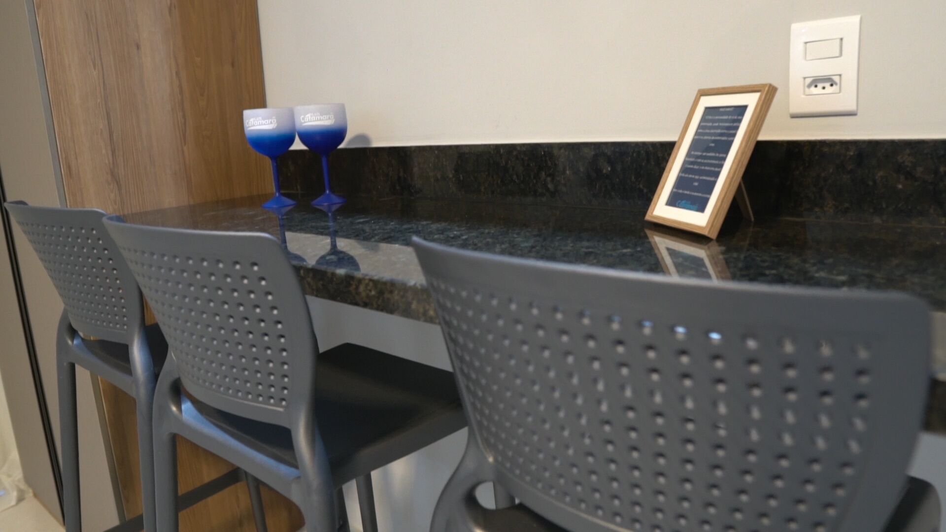 Una encimera de cocina con dos sillas, un certificado enmarcado y dos vasos azules.