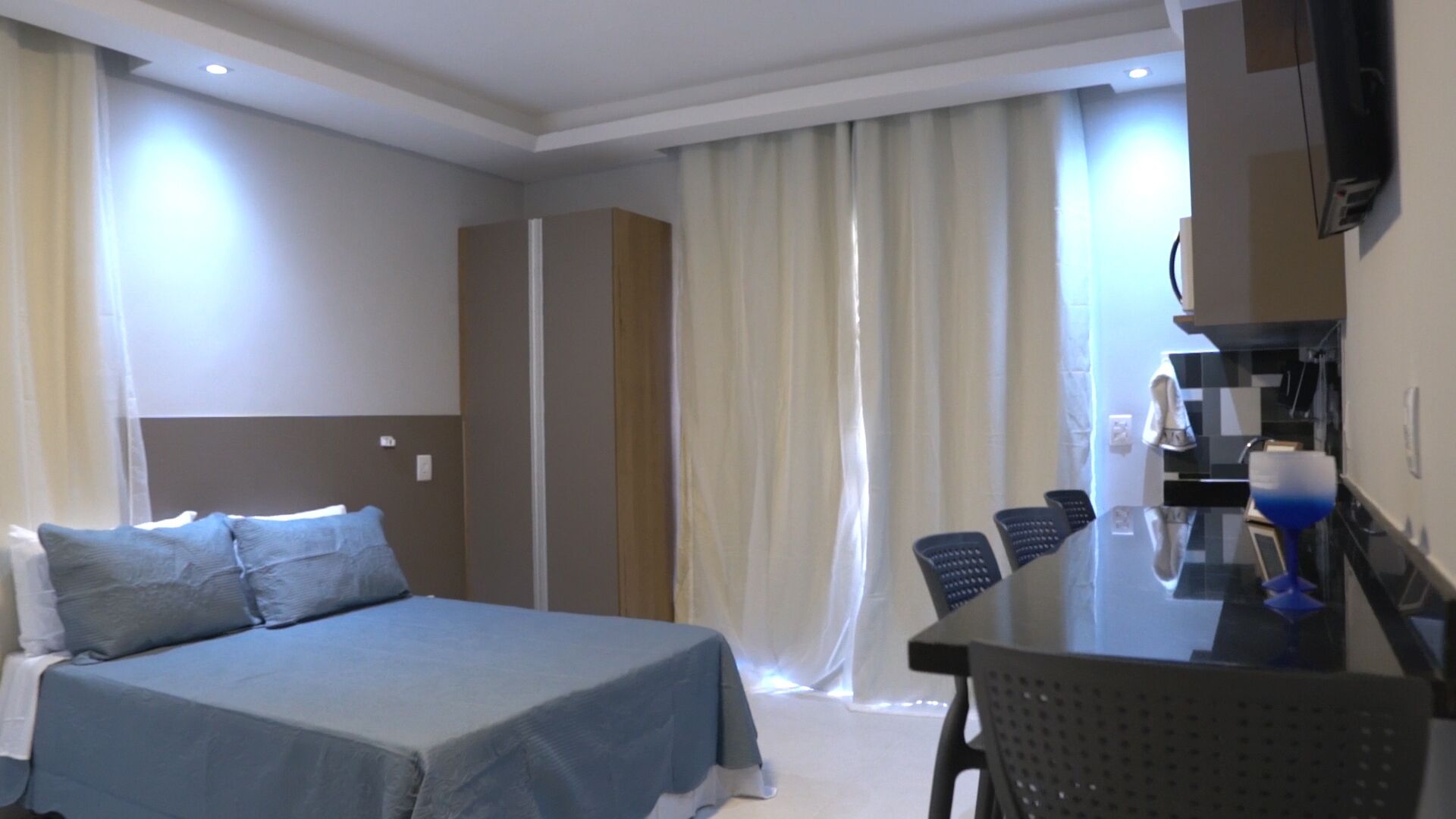 A hotel room with a bed, a desk, chairs, a television, and a bathroom.