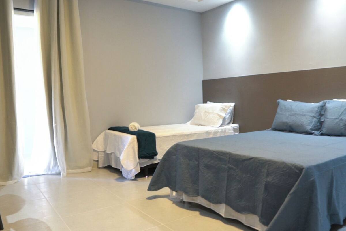 A bedroom with a large bed, a smaller bed, and a chair.
