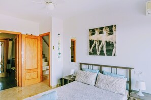 A bedroom with a bed, nightstands, a painting, a staircase, and a door. - Incredible sea view, 3 terraces, pool, parking (Mijas Pueblo)