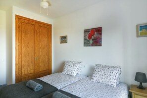 A bedroom with a double bed, a wooden wardrobe, and a painting on the wall.