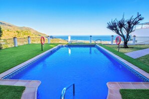 A rectangular swimming pool with a clear blue water feature, surrounded by a low fence and a lifebuoy, with a view of the sea and hills in the background. - Incredible sea view, 3 terraces, pool, parking (Mijas Pueblo)
