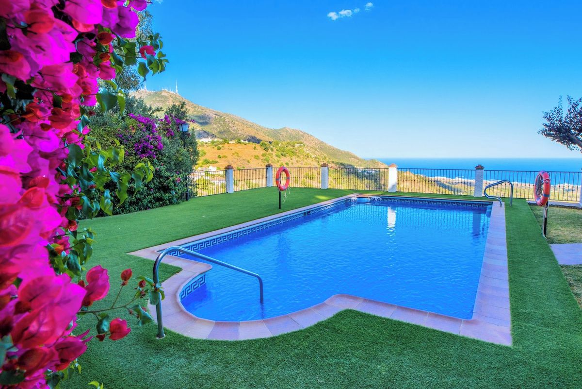 A swimming pool with a view of the sea and hills.