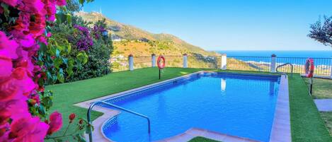 Una piscina con vistas al mar y a las colinas.