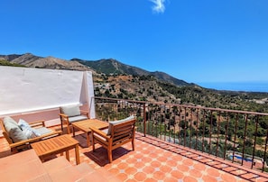 A terrace with outdoor furniture and a view of a mountainous landscape.