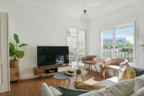 A modern living room with a flat-screen TV, comfortable seating, a dining area, and large windows offering a city view. - Beautiful apartment - short walk to the beach (Benalmadena)