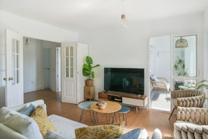 A spacious living room with a large flat-screen TV, a sofa, a coffee table, and a dining area with chairs. - Beautiful apartment - short walk to the beach (Benalmadena)