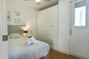 A bedroom with a bed, a nightstand, a lamp, a wardrobe, and a window. - Beautiful apartment - short walk to the beach (Benalmadena)