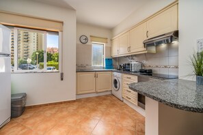 Una cocina moderna con lavadora, microondas y pileta.