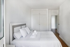 A hotel room with a bed, a wardrobe, and a nightstand.