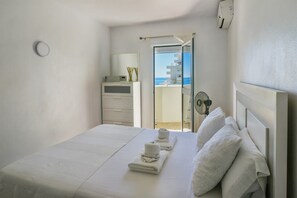 A hotel room with a bed, a small desk, a mirror, and a view of the sea. - Fantastic seaviews & pool, close to the beach (Benalmadena)