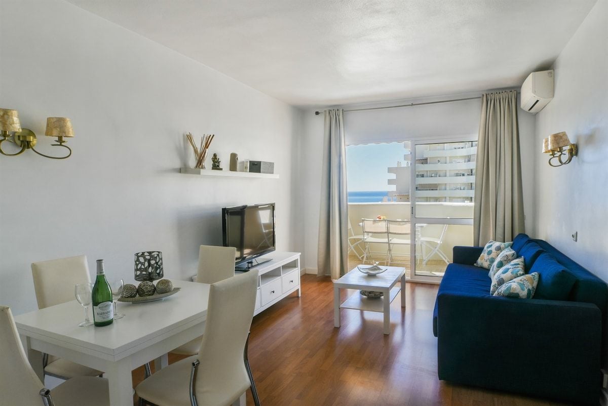 Een moderne woonkamer met een eethoek, een flatscreen televisie en een balkon met uitzicht op zee.
