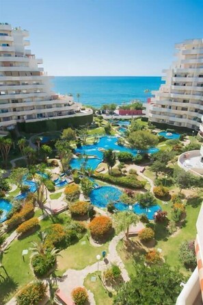 A resort with multiple swimming pools, lush greenery, and a view of the ocean. - Fantastic seaviews & pool, close to the beach (Benalmadena)