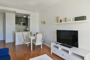 A modern living room with a flat-screen TV, a dining area with a white table and chairs, and a kitchen with grey cabinets and a microwave. - Fantastic seaviews & pool, close to the beach (Benalmadena)